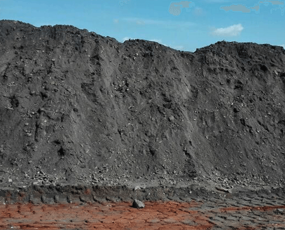 Frontal view of a large stockpile of chrome ore at a warehouse, illustrating the significant reserves available for export amid fluctuating market conditions.